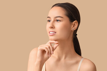 Young woman with hand near her face on beige background. Nose plastic surgery concept