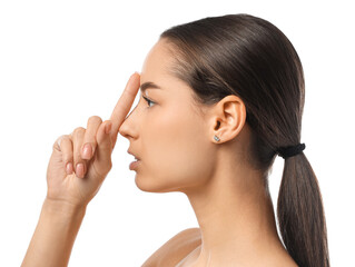 Young woman touching her nose on white background. Plastic surgery concept