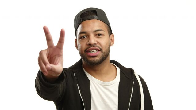 A multiracial young man with glasses and braces makes the peace sign, his face glowing with a joyful expression on a white background. Camera 8K RAW. 