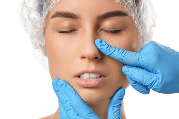 Surgeon hands touching woman nose before plastic surgery on white background, closeup