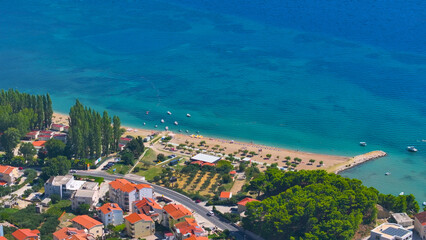 Naklejka premium AERIAL: Residential area of fun coastal town with sandy beach and colorful sea.