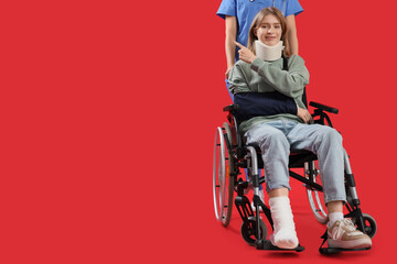 Injured young woman in wheelchair after accident with doctor pointing at something on red background