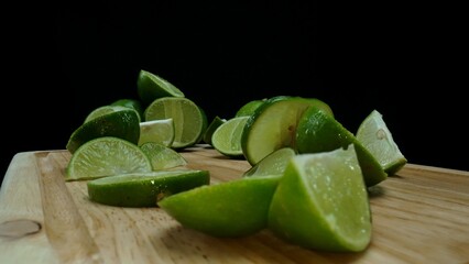 Close-up, a vibrant slice of fresh lime rests upon a rustic wooden cutting board, exuding freshness and vitality. The translucent membranes of the green lime slice placed on cutting board. Comestible.