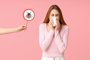 Woman with napkin suffering from allergy and female hand with mite sign on pink background