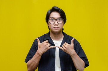 asian young students happily using sign language isolated against yellow background. asian man...