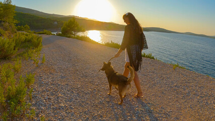 LENS FLARE: Bonding time between a woman and her dog on a scenic morning walk. They are playing...