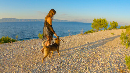 Lady spends quality time with her lovely dog on a morning walk along coastal path on picturesque...