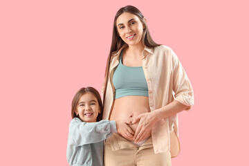 Little girl with her pregnant mother on pink background