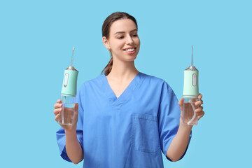 Female dentist with oral irrigators on blue background