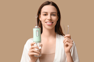 Happy young woman with oral irrigator on brown background