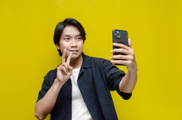 excited young asian man holding phone while dancing and pointing to copy space with full of amazement.