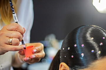 stylist decorating hair with small stones for a ballroom sports tournament, non-Olympic sport