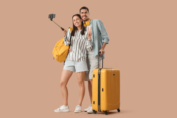 Beautiful young happy couple of tourists with suitcase and backpack taking selfie on brown...