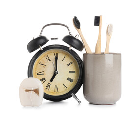 Black alarm clock, dental floss and toothbrushes isolated on white background