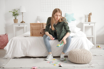 Tired young mother resting in bedroom with scattered toys on floor