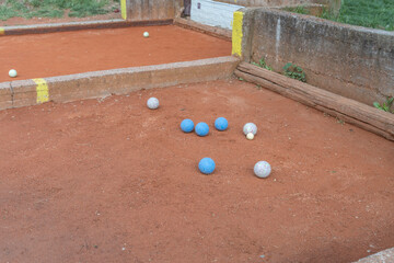  leisure and sport, featuring a group of boules, or pétanque, balls on a red clay court. The focus...