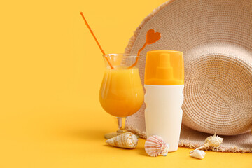 Bottle of sunscreen cream, glass of juice, seashells and hat on color background