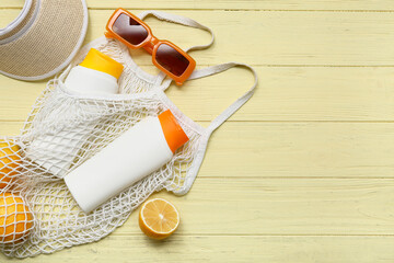 String bag with beach accessories and lemons on wooden background