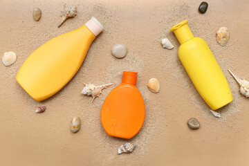 Bottles of sunscreen cream with seashells and sand on brown background