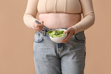 Overweight woman with salad on beige background. Diet concept