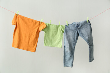 Clean clothes hanging on rope against grey background