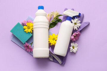 Set of cleaning supplies and spring flowers on lilac background