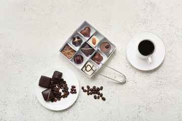 Box with candies, plate, coffee beans, cup of coffee and kitchen tongs on light background