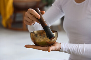 Sporty young woman with Tibetan bowl practicing yoga at home, closeup