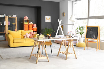 Interior of beautiful childrens room with workplace, toys and yellow sofa