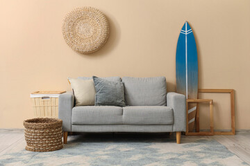 Grey sofa and surf board near beige wall in stylish living room