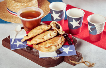empanadas de pino y mote con huesillos junto a vasos con bandera de Chile, celebración fiestas...