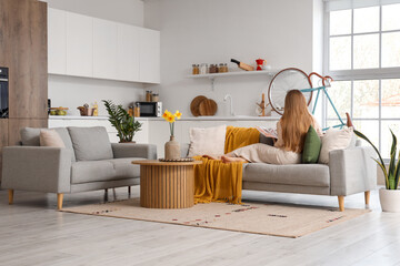 Young woman resting on comfortable sofa in living room