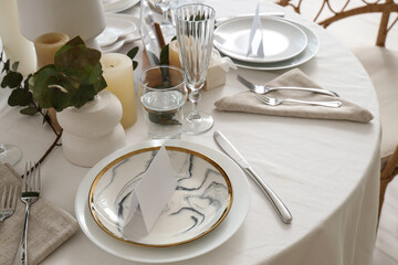 Beautiful table setting with eucalyptus and candles for wedding celebration in room, closeup