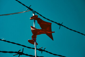 close-up of a broken balloon hanging on barbed wire - Powered by Adobe