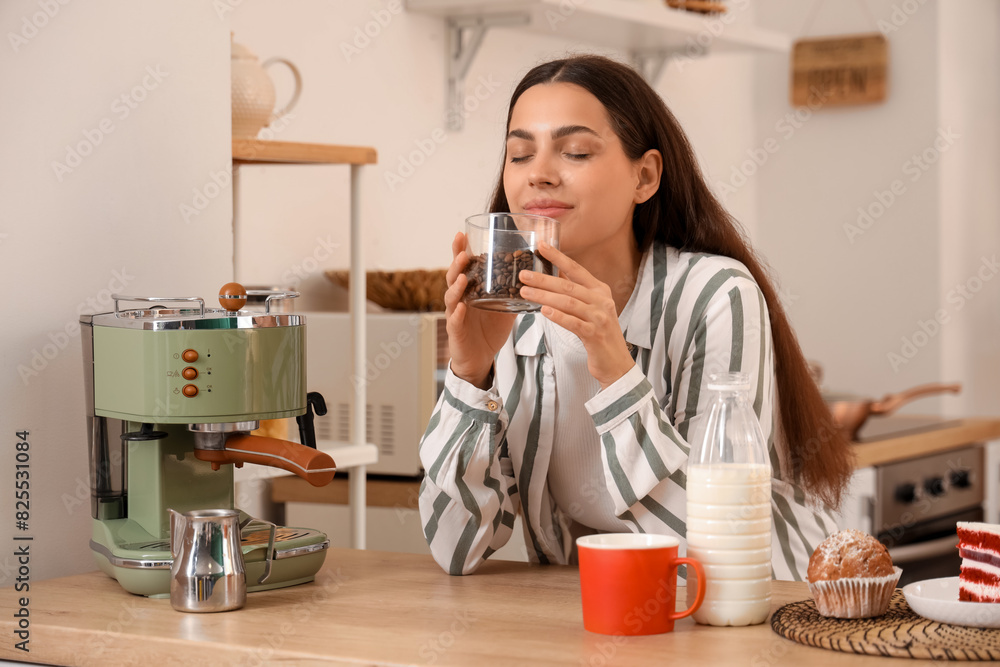 Wall mural beautiful young happy woman with modern coffee machine and jar of fresh beans in kitchen