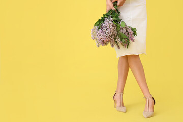 Young woman with bouquet of blooming lilac flowers on yellow background, closeup