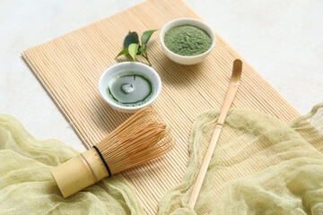 Bowls of matcha tea and powder with chasen on white background