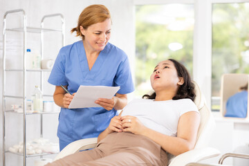 Obraz premium Skilled middle-aged doctor assisting patient in consulting with help of documentation