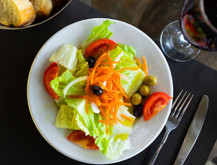 There are large pieces of fresh vegetables on plate. Vitamin salad of fresh vegetables, lettuce,...