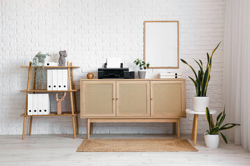 Interior of light office with printer on commode, plants and shelf unit