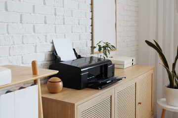 Modern printer on commode near white brick wall in office