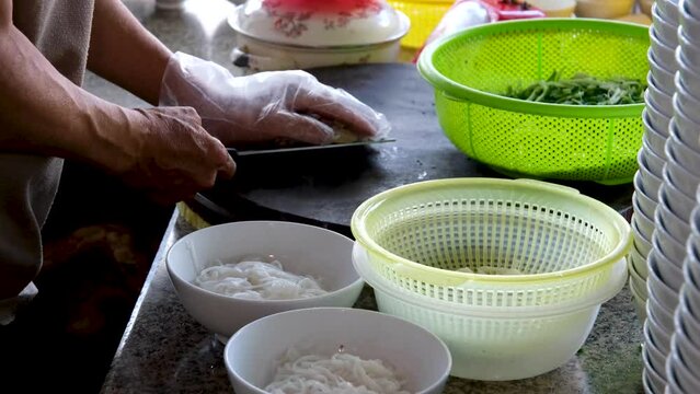Vietnamese pho soup male seller preparing rice vermicelli soup on the street small eatery cooking fa soup in Vietnam street food dirt unsanitary conditions delicious travel tourists local population