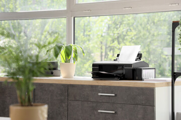Modern printer on table near window in office