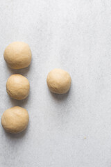 Overhead view of egg noodles dough on a marble countertop, homemade egg noodles and egg pasta dough balls, process of making fresh egg noodles