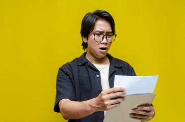 asian man opening envelope receiving and reading bad news letter. An angry man is upset over his...