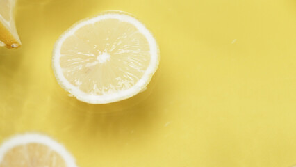 Lemon slices on wavy water surface. Close up lemon sliced placed at yellow background and water wave. Natural light. Macro. Freshness and hydration concept. Design for poster, greeting card. Pabulum. - Powered by Adobe