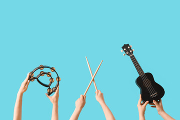 Women with tambourine, drumsticks and ukulele on blue background