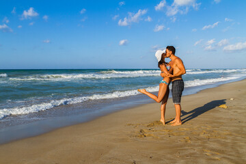 Young couple embracing and kissing at the beach in late summer at dusk.