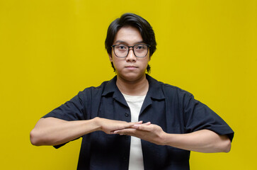 asian young students happily using sign language isolated against yellow background. asian man...