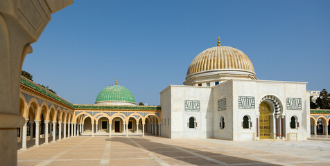 White marble building of Habib Bourguiba Mausoleum in Monastir, topped with gold and green domes,...